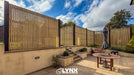 Outdoor patio area with wooden privacy screen, table, chairs, and plants on a sunny day.